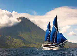 SeaTrek's Ombak Putih passing one of Indonesia’s many volcanoes under full sail.